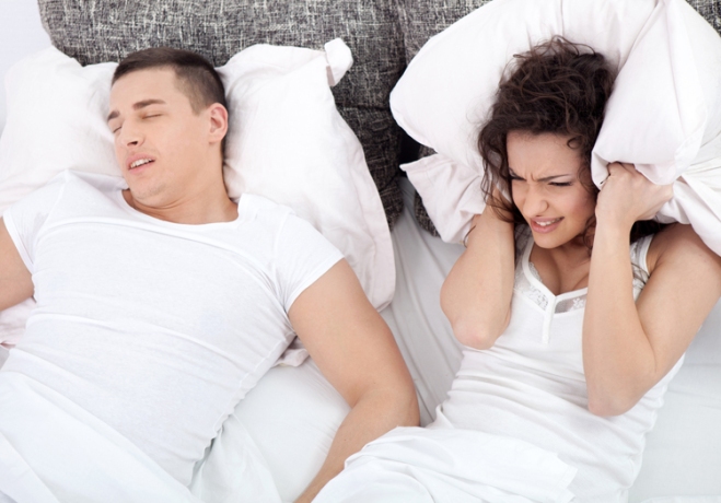 Snoring man and young woman. Couple sleeping in bed.